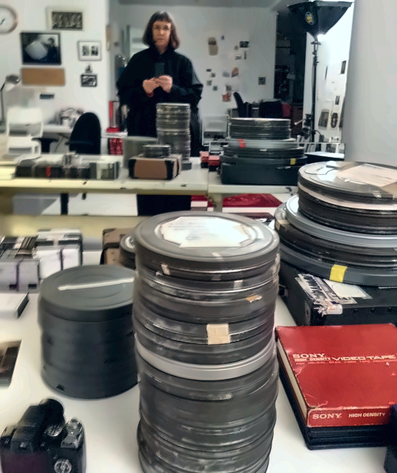Eleanor Claire Johnson standing behind stacked film cans in her East 57th Street studio.